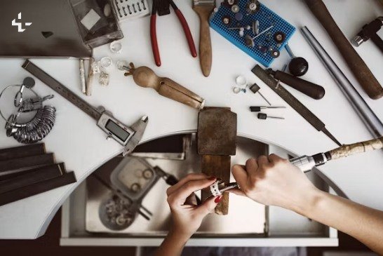 A maker working at a bench, hands shaping a small part among well-used tools