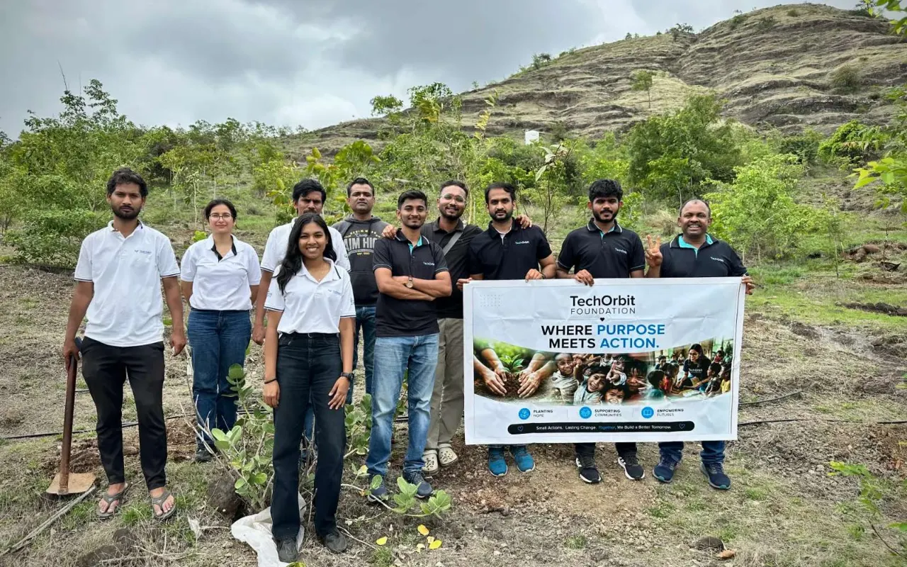 Volunteers at the Project GreenRoots plantation drive, holding the TechOrbit Foundation banner on a hillside